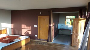 Quarto com cama, porta para uma cozinha e janela.