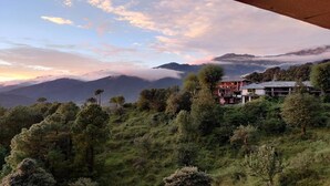 Paisagem montanhosa com uma casa rodeada por floresta densa.