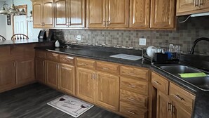 Una cocina con armarios de madera, encimera negra y salpicadero de azulejos.