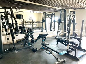 A gym with various exercise equipment, including weight machines and benches. - Comfortable apartment with ocean view, on España Avenue. (Santo Domingo Este)