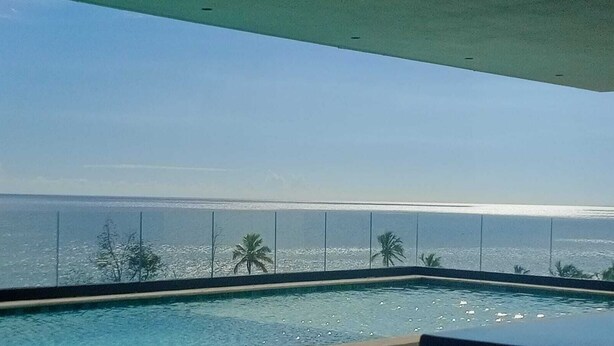 A swimming pool with a view of the ocean and palm trees.