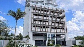 A modern high-rise building with multiple balconies and a gated entrance.