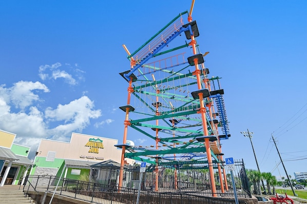 An outdoor adventure park with a climbing structure and a building labeled 'Adventure Zone.' - Summer Place #303 (Fort Walton Beach)