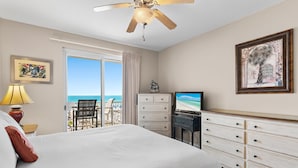 Een hotelkamer met een bed, een dressoir, een televisie en een balkon met uitzicht op zee.