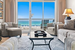 A living room with a view of the ocean, a sofa, a coffee table, and a lamp. - Summer Place #303 (Fort Walton Beach)