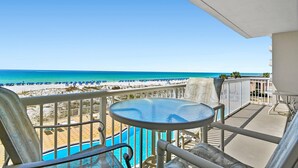 Een balkon met uitzicht op een strand en een zwembad.