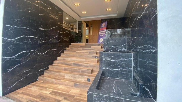 A staircase with black marble walls and wooden steps leading to a reception area. - Apartment with modern design (Ciudad de México)