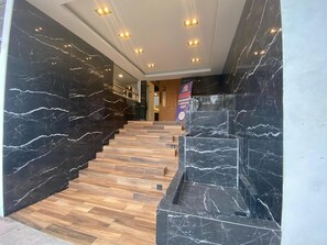 A staircase with black marble walls and wooden steps leading to a reception area. - Apartment with modern design (Ciudad de México)