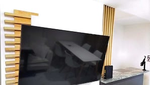 A modern living room with a large flat-screen TV mounted on a wooden slat wall. - Apartment with modern design (Ciudad de México)