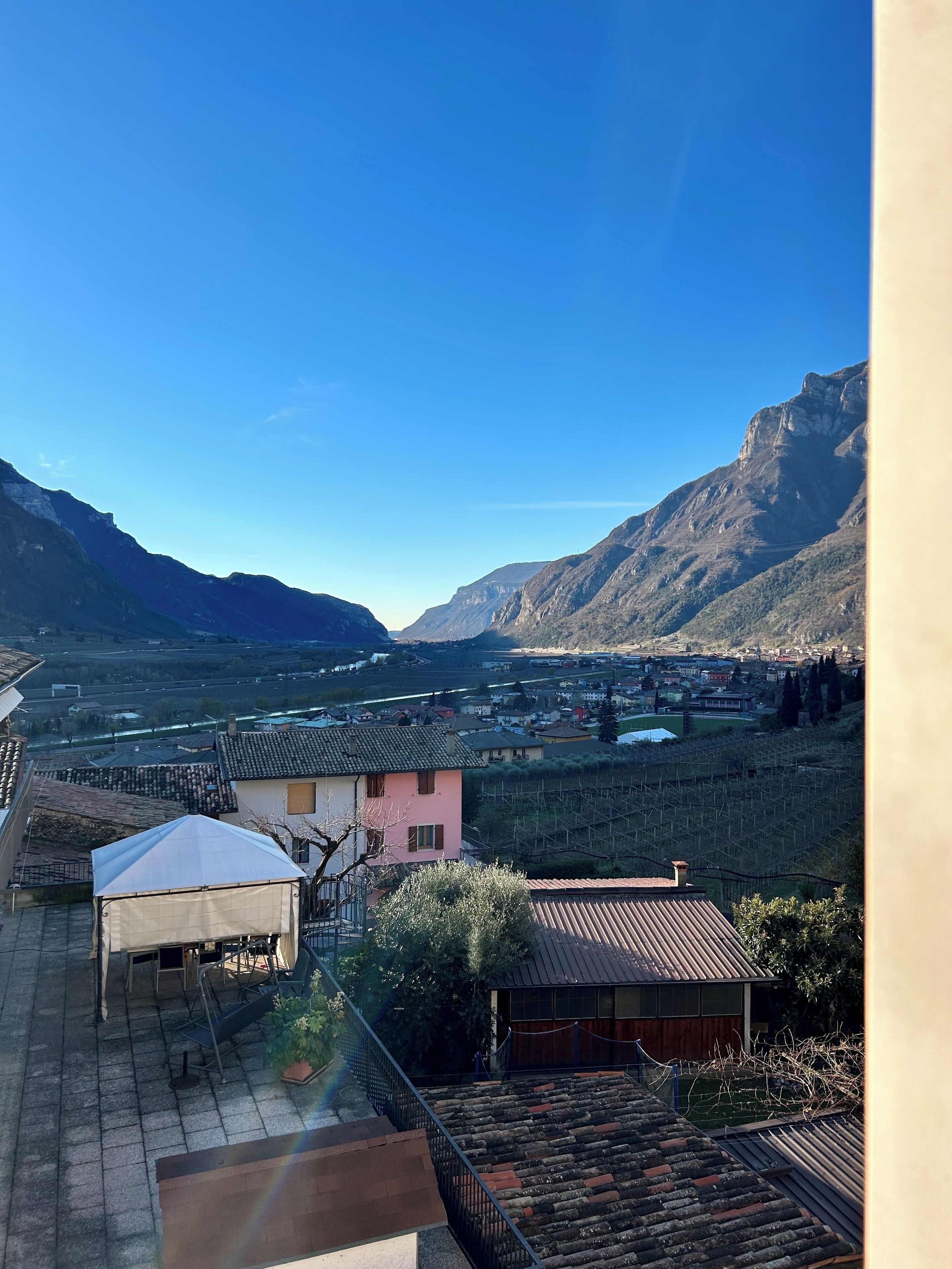 Un quartier résidentiel offrant une vue sur les montagnes, avec une maison rose et un patio couvert.