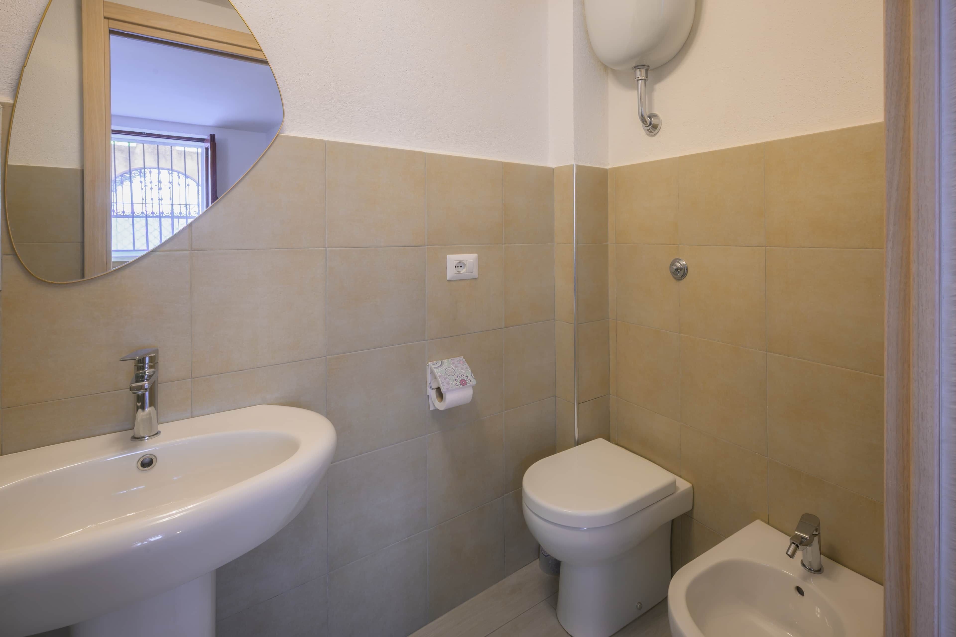 Une salle de bain équipée d’un lavabo, de toilettes, d’un bidet et d’un miroir.