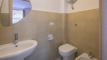Une salle de bain équipée d’un lavabo, de toilettes, d’un bidet et d’un miroir.