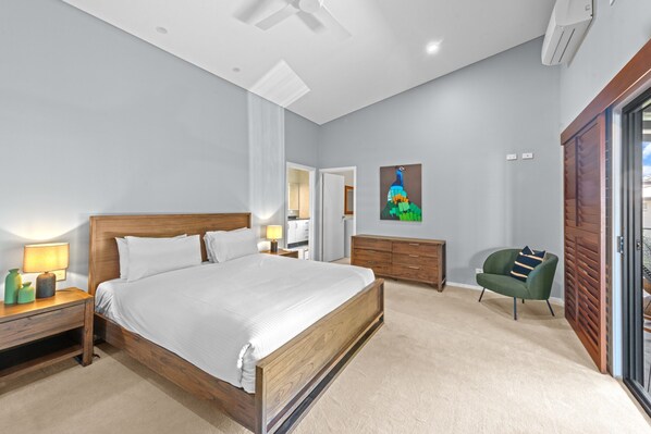 A bedroom with a wooden bed, a nightstand, a dresser, a chair, and a painting on the wall. - Family-sized Retreat With Private Garage (Brisbane)