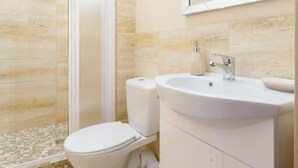 A modern bathroom with a toilet, sink, and shower. - Nika Apart Hotel  (Riga)