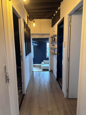 Een gang met houten vloer, een blauwe muur en een witte deur aan de rechterkant.