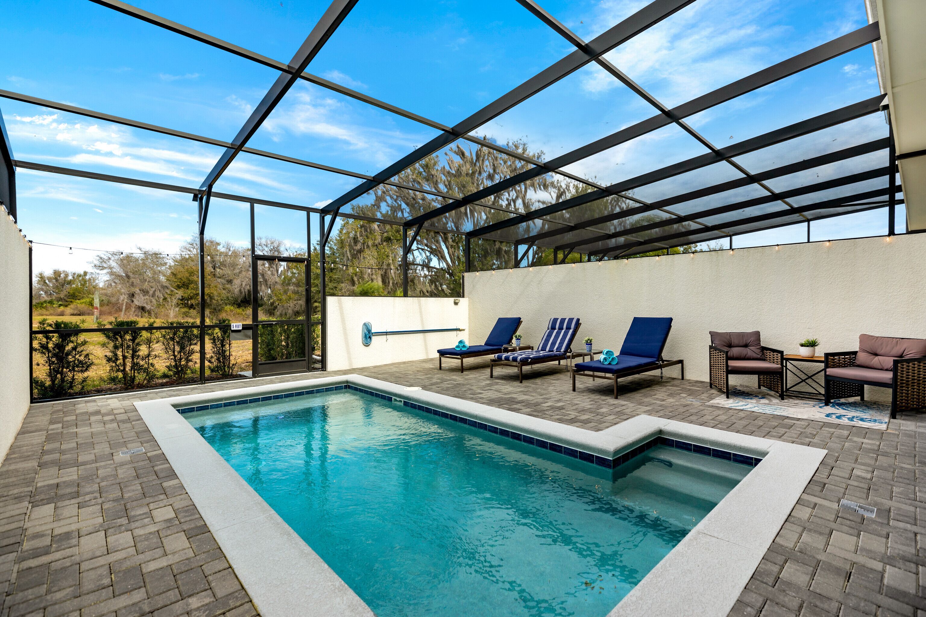 Una piscina interior con techo de vidrio, rodeada de sillones de descanso y una pequeña mesa con una planta.