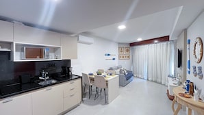A modern kitchen with a dining area, a sofa, and a TV. - Carneiros Atlantico Beira-mar - Proximo da Igrejinha (Tamandaré)