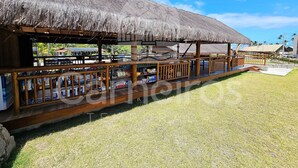 A beachside restaurant with a thatched roof, wooden deck, and outdoor seating. - Carneiros Atlantico Beira-mar - Proximo da Igrejinha (Tamandaré)