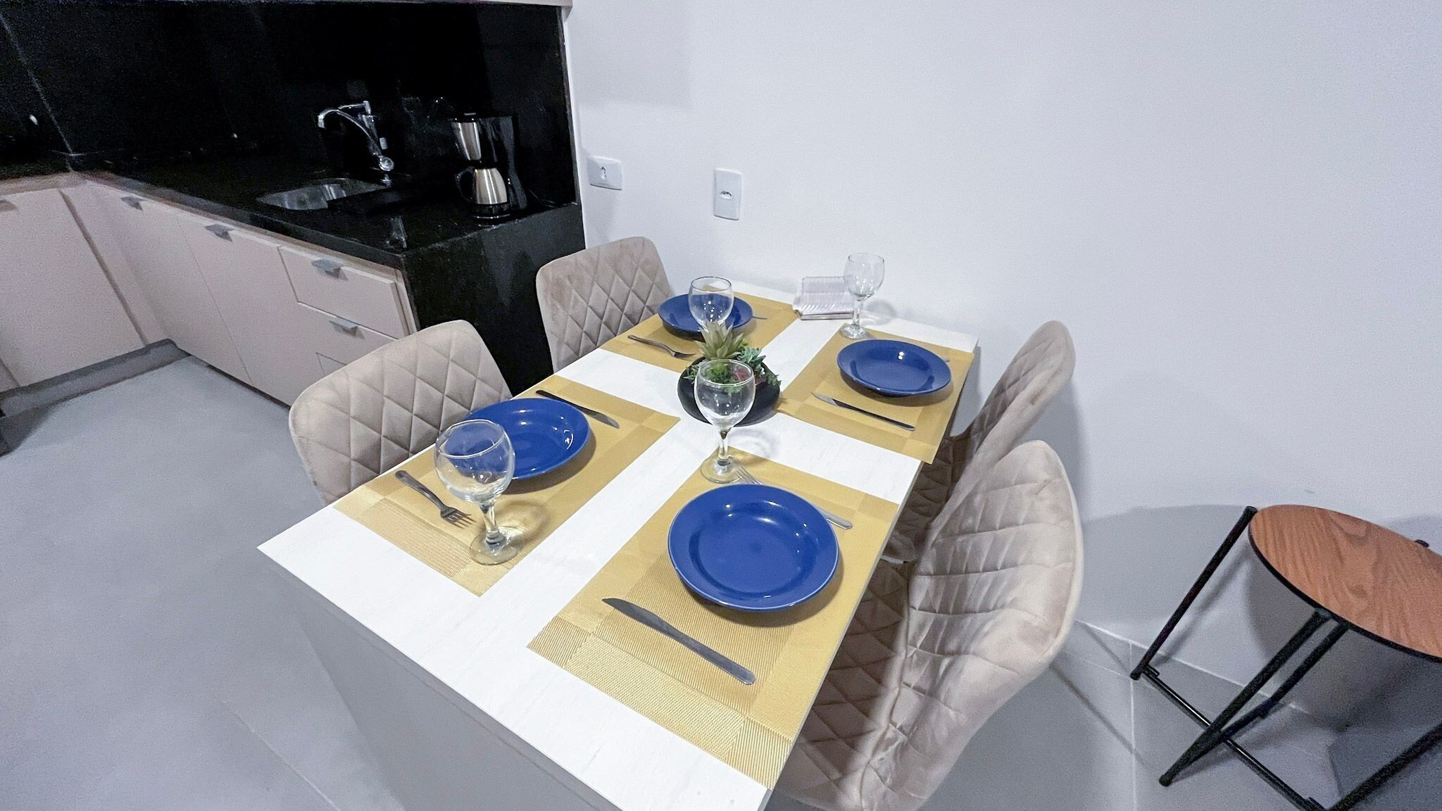 Une table à manger dressée avec des assiettes bleues, un verre à vin et des couverts.
