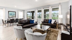 A modern living room with two sofas, a coffee table, and a dining area with chairs and a table. - Last Minute Disney! Private Pool, Hot Tub, Game Room & Themed Bedrooms. Book Now! #45514 (Orlando)