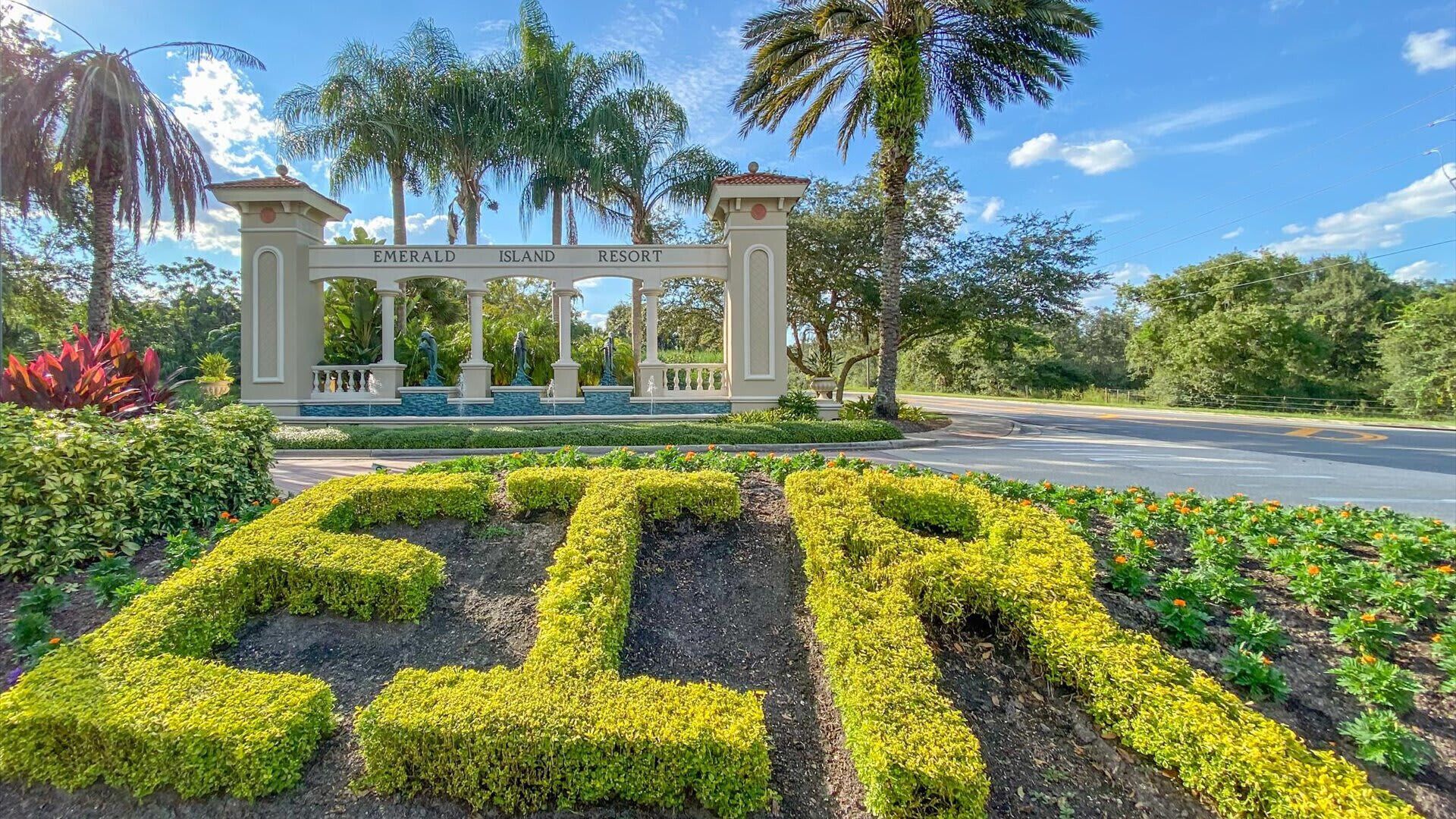 Bordje voor Emerald Island Resort met een aangelegde tuin met geometrische haagpatronen.