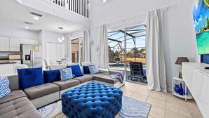 A modern living room with a sectional sofa, ottoman, and a view of a swimming pool.