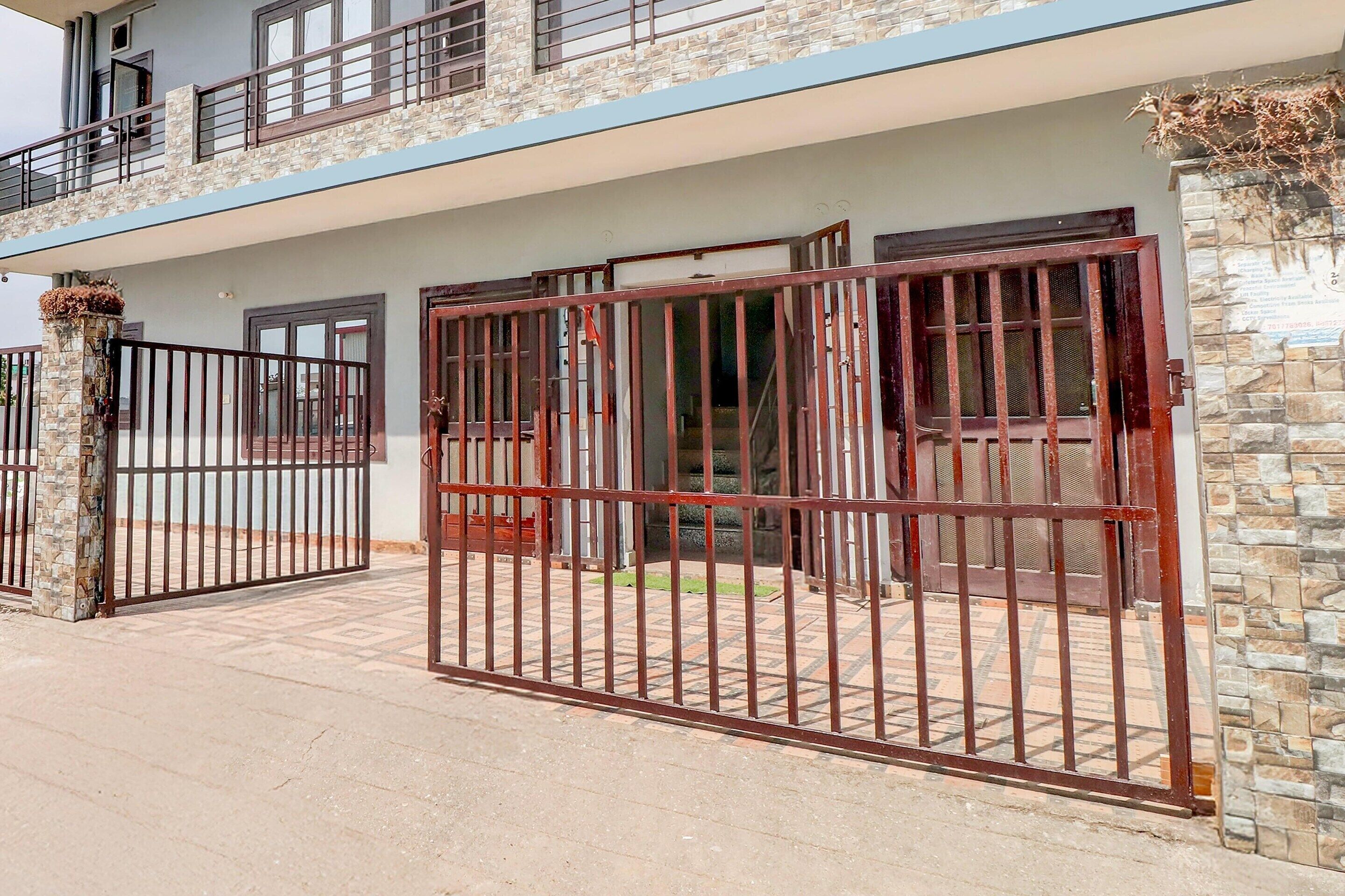 A two-story building with a gated entrance, stone facade, and a balcony.