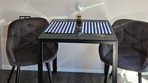 Una habitació amb una taula negra, dues cadires marrons, un televisor penjat i elements decoratius a la paret.