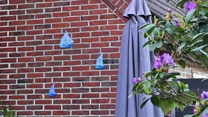 Un mur de maons amb dues cadires blaves i blanques a ratlles i un parasol gris.
