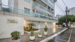 Un bâtiment moderne avec une enseigne indiquant « ED. HENR » et « VALLON 26 ». Des plantes en pot sont disposées le long du trottoir, et une zone de stationnement est délimitée par des lignes jaunes.