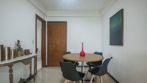Un coin repas avec une table ronde, quatre chaises, une porte en bois, un mur blanc et un tableau encadré.