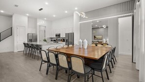 A modern kitchen with white cabinets, a wooden dining table, and black chairs. - Last Minute Disney Getaway! Luxury Villa with Private Pool, Hot Tub & Themed Bedrooms. Book Now! #147189 (Orlando)