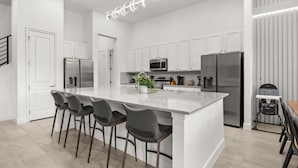 A modern kitchen with white cabinetry, stainless steel appliances, and a central island with bar stools. - Last Minute Disney Getaway! Luxury Villa with Private Pool, Hot Tub & Themed Bedrooms. Book Now! #147189 (Orlando)