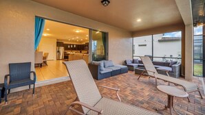 Eine überdachte Terrasse mit Rattanmöbeln, einer Couch und Blick ins Haus.