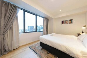 A hotel room with a large window, a bed, a nightstand, and a lamp. - Southbank 2BDR With Views Gym Pool And Sauna (Southbank)