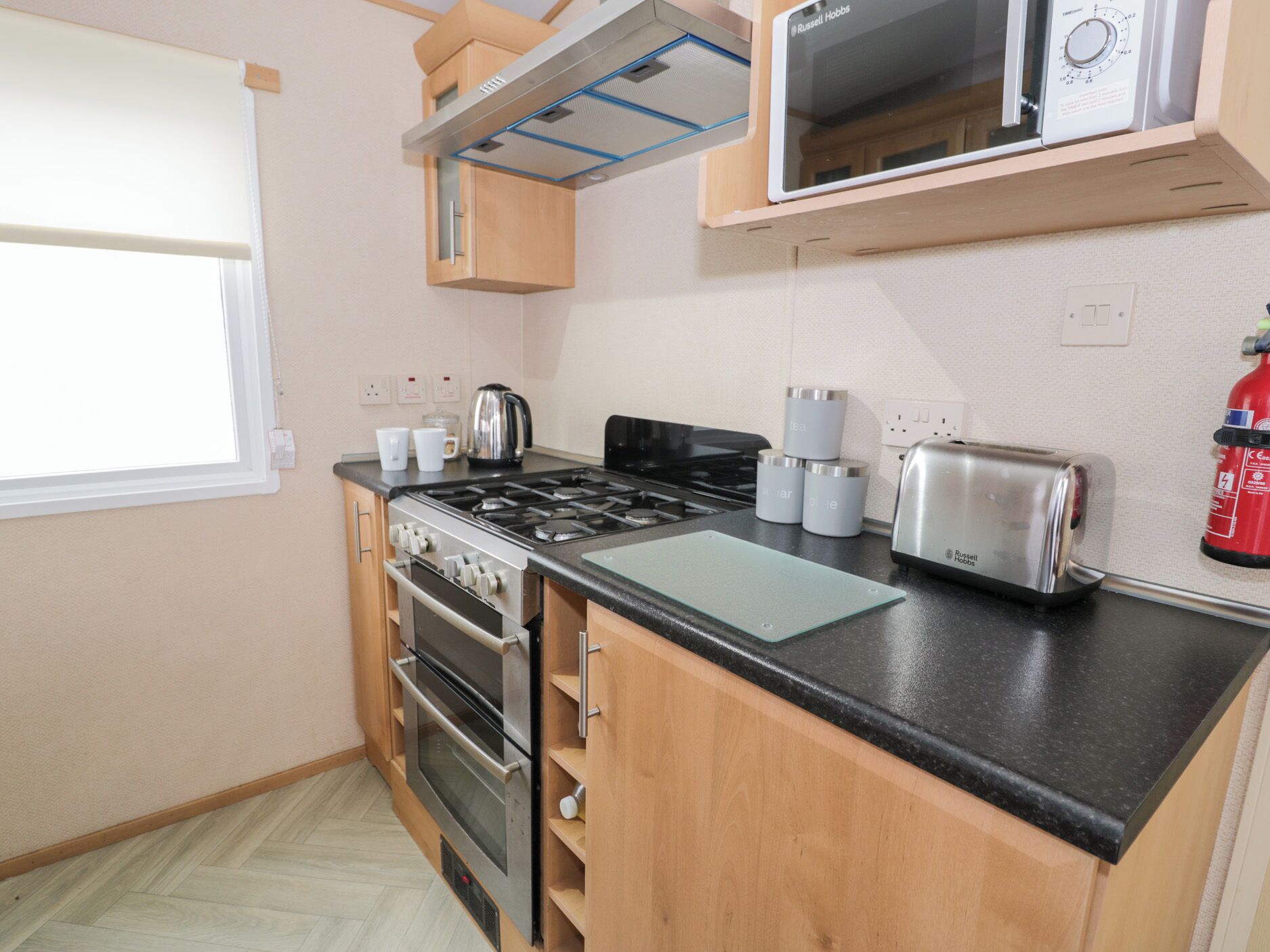 A compact kitchen with a gas stove, oven, microwave, and toaster.