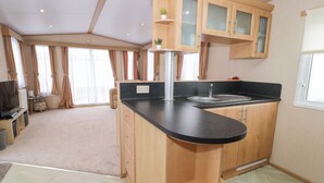 A compact kitchen with wooden cabinets, a black countertop, and a built-in sink. - 11, Beachfields (Rhyl)