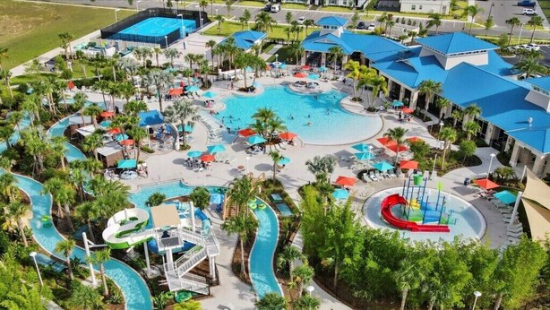 Vista aérea de un resort con varias piscinas, toboganes acuáticos y palmeras.