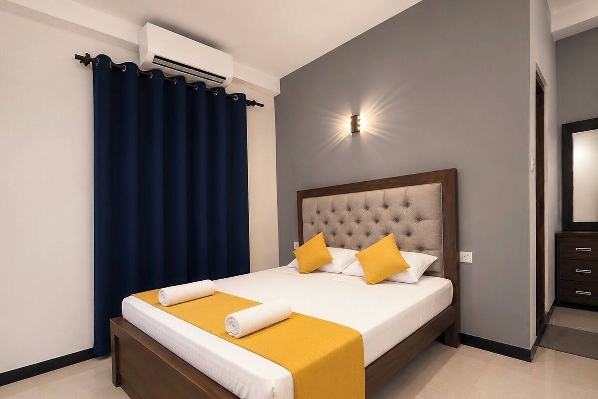 Una habitación de hotel con una cama, una mesita de noche, un espejo y un aire acondicionado.