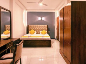 Une chambre à coucher comprenant un lit, un bureau, une chaise, une armoire et un ventilateur de plafond.