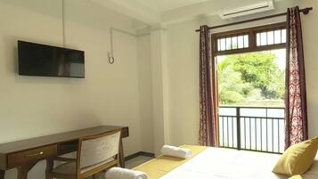 Una habitación de hotel con cama, escritorio, silla, televisión y ventana con cortinas.