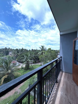 Un balcón con vistas a un paisaje verde exuberante y palmeras.
