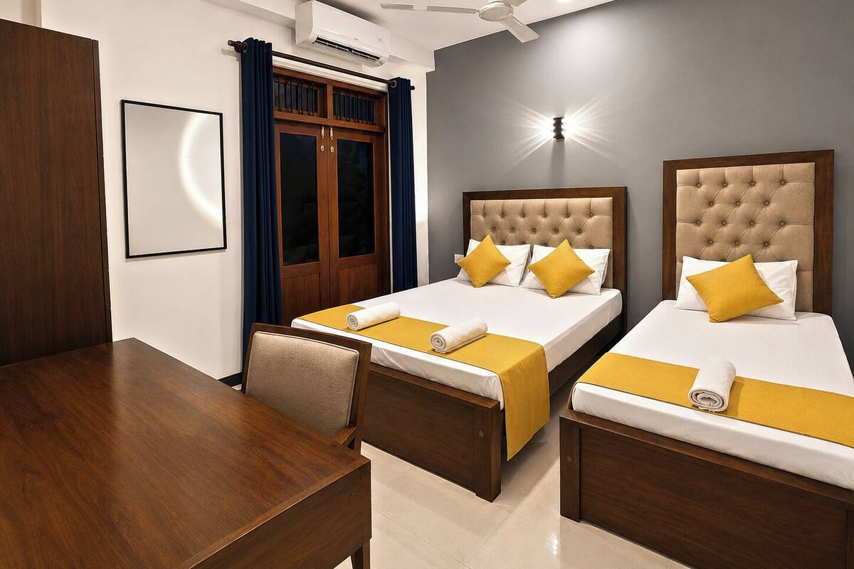 Habitación de hotel con dos camas, un escritorio, una silla, un armario, un aire acondicionado y un ventilador de techo.