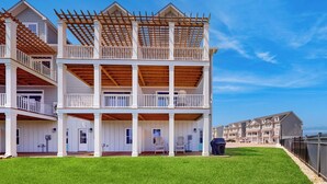 A multi-story residential building with a covered porch and a fenced yard.