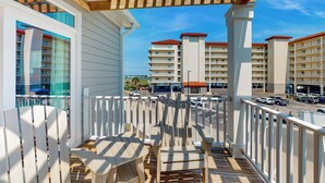 A balcony with a wooden pergola, white railings, and a view of multi-story buildings with red roofs.