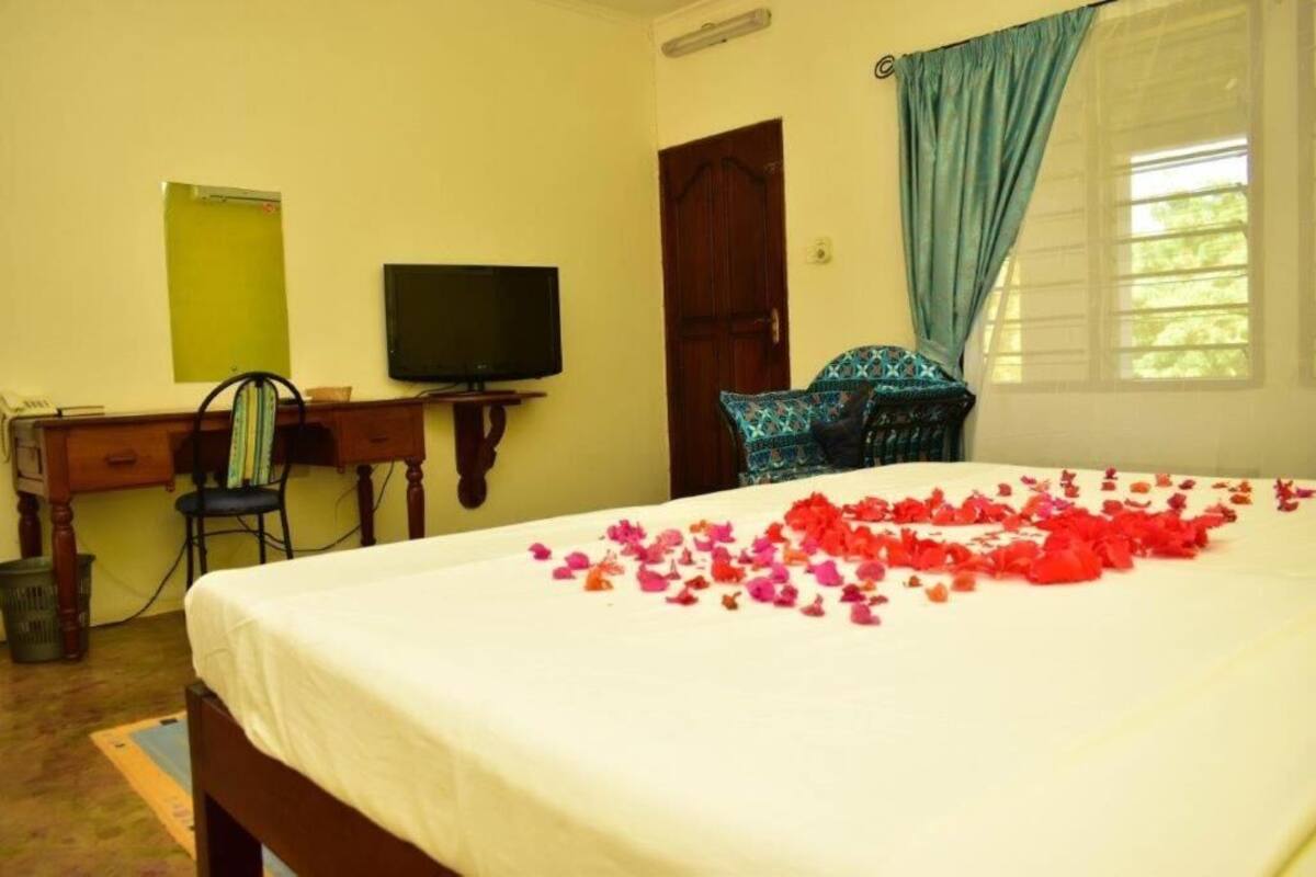A hotel room with a bed, a desk, a television, and a window with curtains.