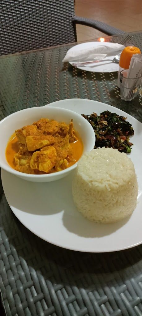 A plate with white rice, a bowl of curry, and a side of mixed vegetables.