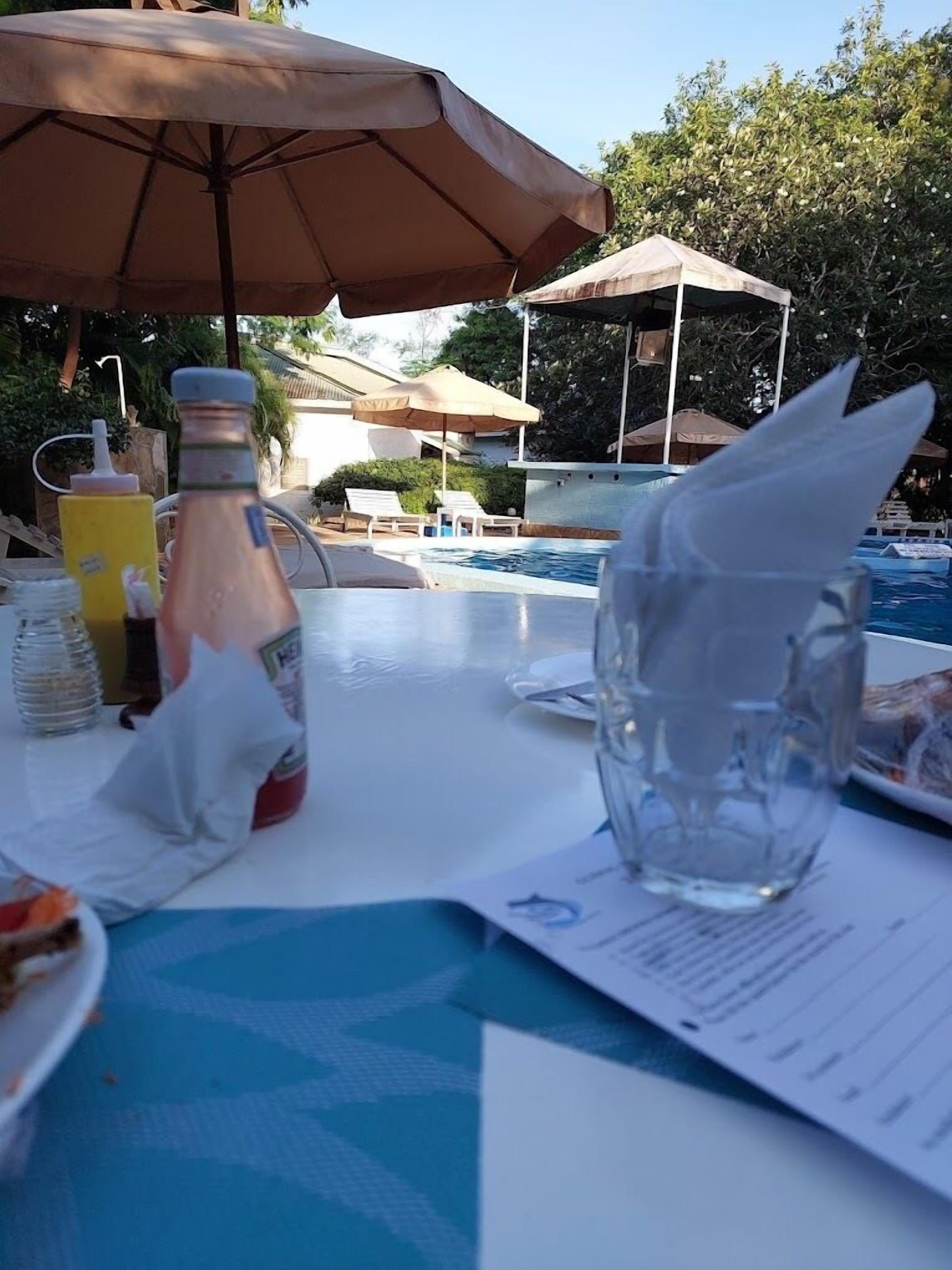 Een tafel met een fles, een glazen pitcher en een menukaart bij een zwembad.
