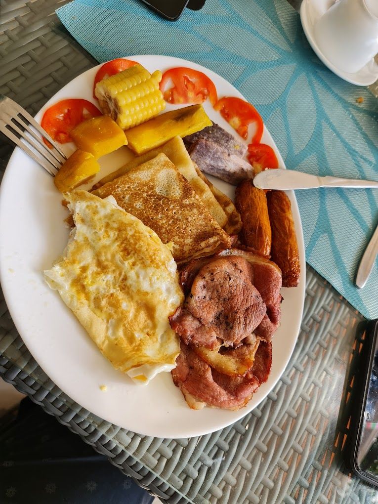 Un plato de comida para el desayuno con huevos, salchichas y elote.