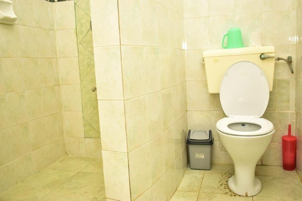 Ein kleines Badezimmer mit Toilette, Mülleimer und Toilettenbürste.